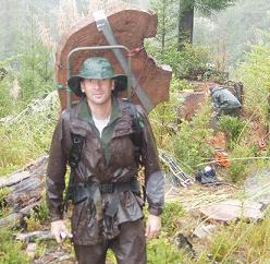 Greg Jennings hiking through mud and rain with a heavy stump fire history sample.
